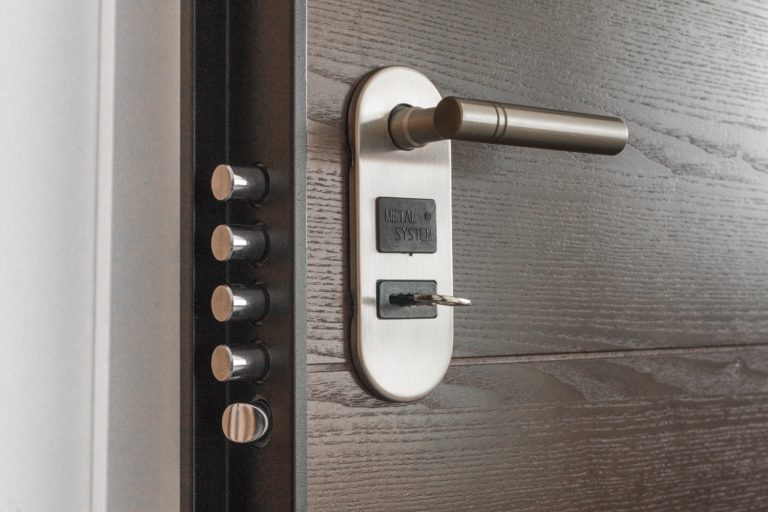 Serrure de porte en bois foncé avec poignée métallique et clé engagée, symbole de l'entrée dans un logement