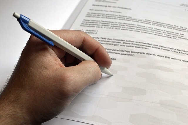 Main tenant un stylo au-dessus d'un document imprimé, au moment de la signature