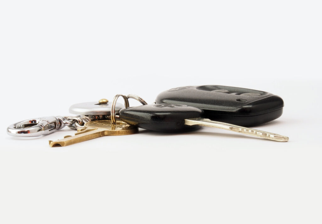 Clés et télécommande d'une voiture posées sur un fond blanc