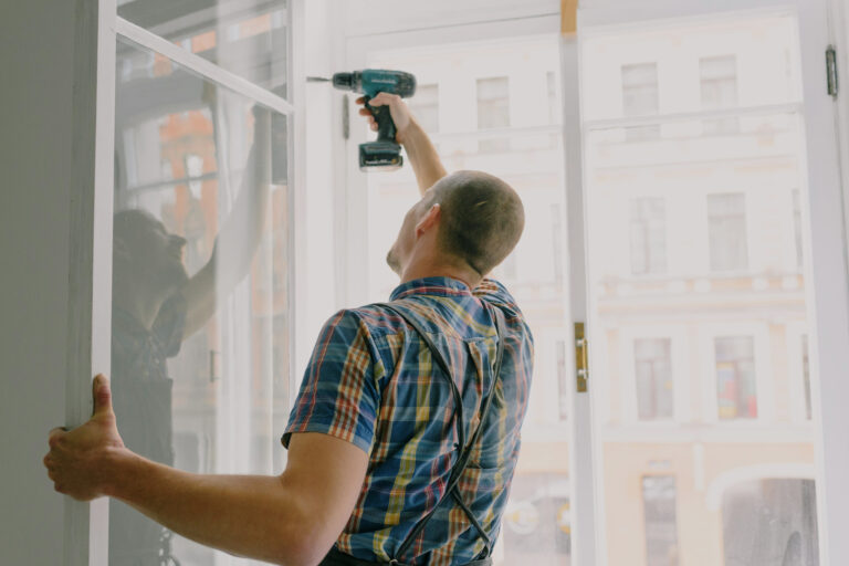 Artisan qui fixe un châssis de fenêtre dans une habitation en rénovation